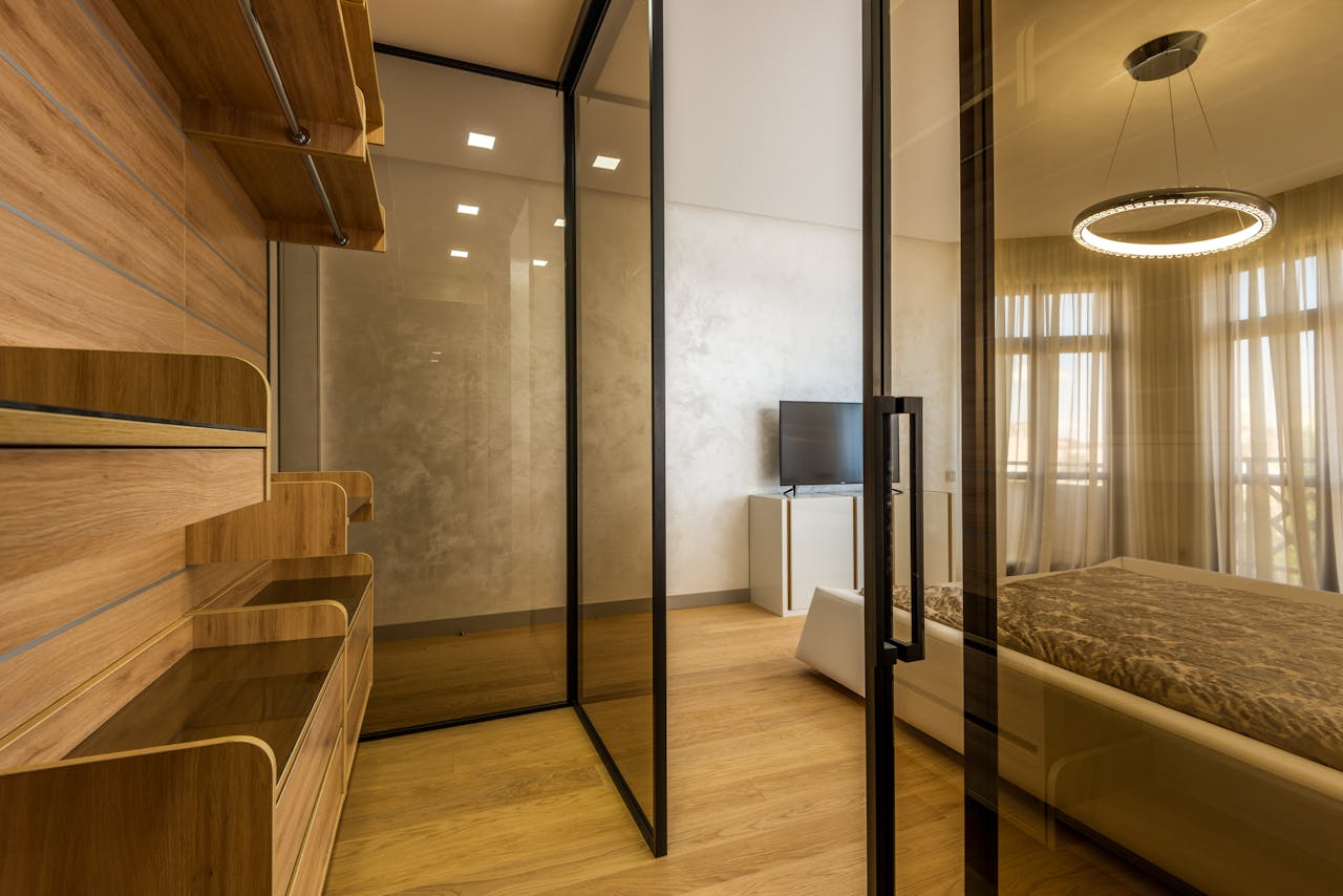 Elegant bedroom featuring contemporary design, glass partitions, and warm lighting.